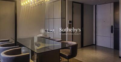 Modern dining area with glass table and upholstered chairs, featuring contemporary lighting and built-in cabinetry