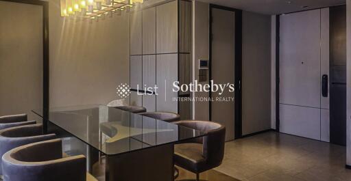 Modern dining area with glass table and upholstered chairs, featuring contemporary lighting and built-in cabinetry