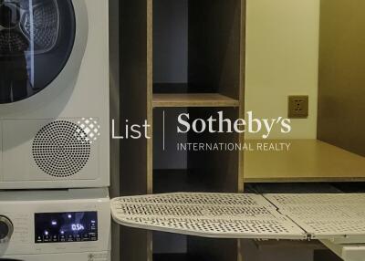 Laundry room with stacked washer and dryer, ironing board, and storage shelves