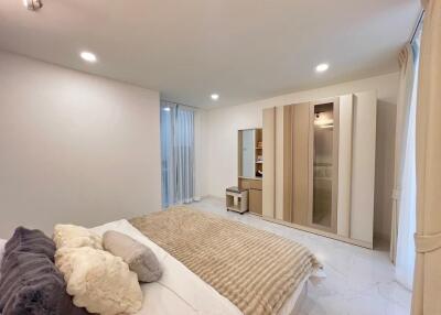 Spacious well-lit bedroom with large wardrobe and bed