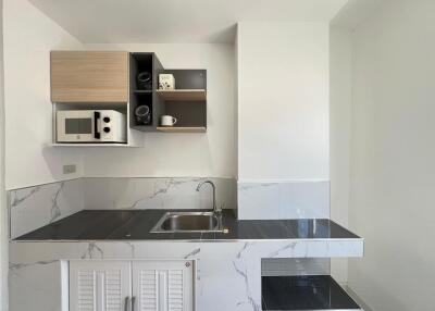 Modern kitchenette with marble countertop and storage cabinets