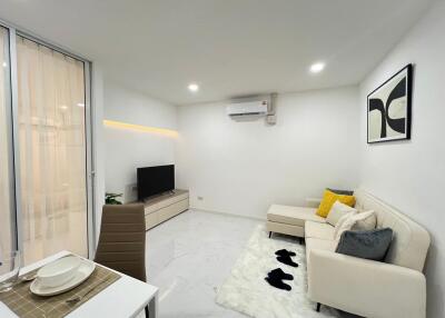 Modern living room with white walls, air conditioning unit, and a sectional sofa