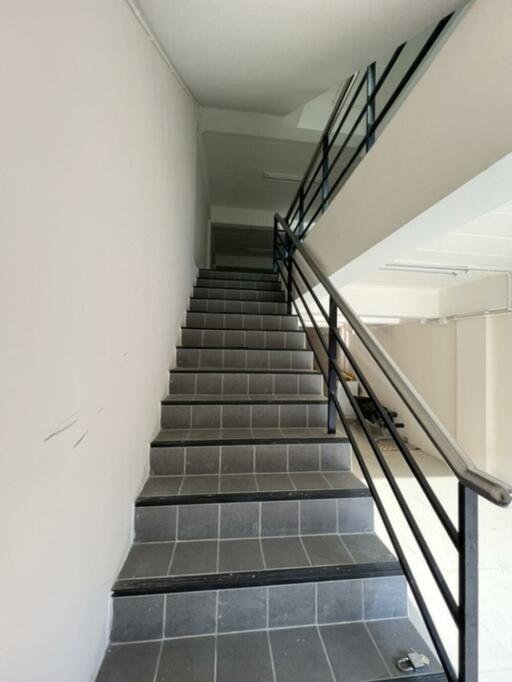 Staircase with black tiled steps and metal handrails