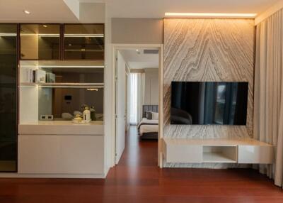 Modern living room with TV, built-in cabinets, and view into bedroom