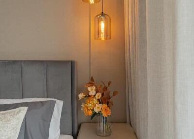 Cozy bedroom corner with bedside table, modern lamps, and fresh flowers