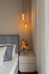 Cozy bedroom corner with bedside table, modern lamps, and fresh flowers