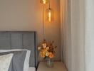 Cozy bedroom corner with bedside table, modern lamps, and fresh flowers