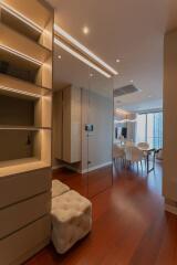 Modern living area with wooden flooring, glass wall, and dining set