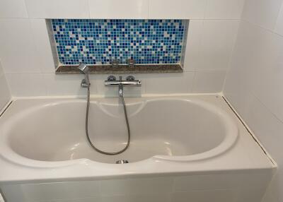 Bathtub with blue mosaic tile in the bathroom