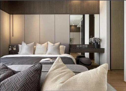 Modern, cozy bedroom with neutral tones, decorative pillows, bedside table, and a large mirror