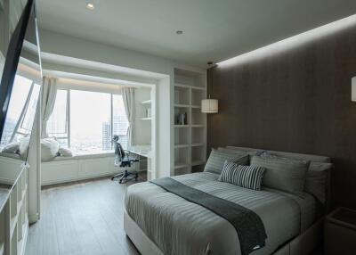 Modern bedroom with a city view, queen size bed, and workspace.