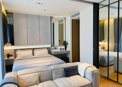 Modern bedroom with a bed, sofa, and mirrored wardrobe