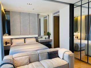 Modern bedroom with a bed, sofa, and mirrored wardrobe