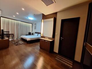 Spacious bedroom with wooden flooring, bed, and furniture