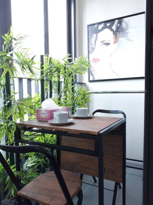 Cozy balcony seating area with a small table and chairs, adorned with plants and artwork