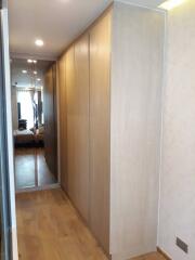 A hallway with built-in wooden closets and mirrors