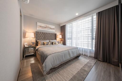 A well-lit modern bedroom with a large bed, nightstands, and lamps.