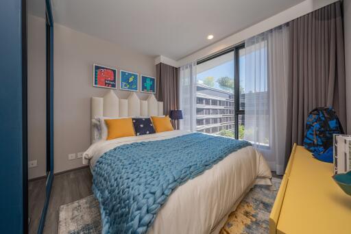 Modern bedroom with large bed, vibrant decor, and city view.