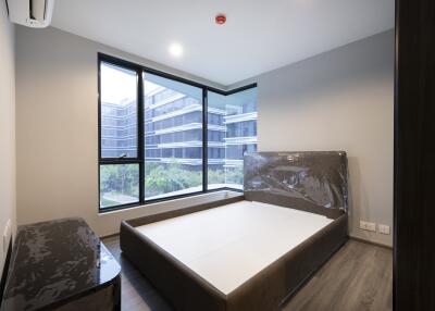 Modern bedroom with large windows overlooking buildings