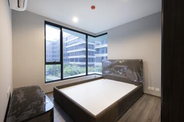 Modern bedroom with large windows overlooking buildings