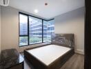 Modern bedroom with large windows overlooking buildings