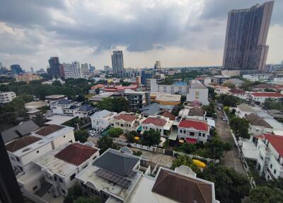 Aerial view of a residential neighborhood with various buildings, greenery, and distant cityscape