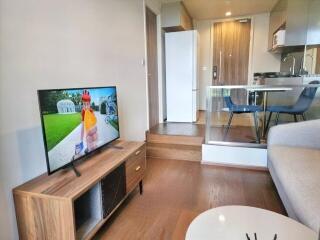 Modern living room connected to kitchen area with wooden furniture and large TV