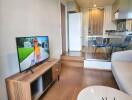 Modern living room connected to kitchen area with wooden furniture and large TV