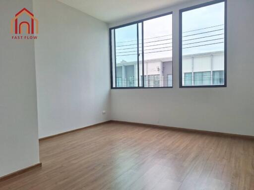 Bright empty bedroom with large windows and wooden flooring