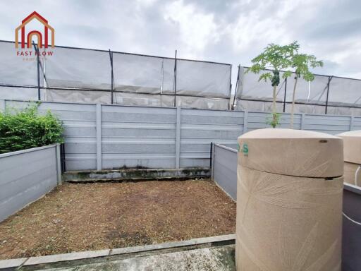 Enclosed backyard with water tanks and potted plant