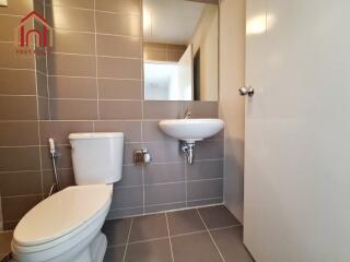 Modern bathroom with tiled walls and flooring, white sink and toilet.