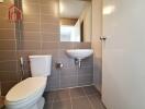 Modern bathroom with tiled walls and flooring, white sink and toilet.