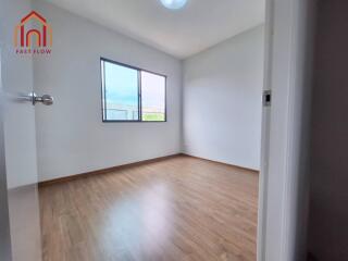 Spacious bedroom with wooden flooring and large window