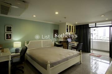 Spacious and well-lit bedroom with a bed, desk, and window view