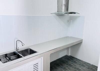 Modern white kitchen with ventilation hood, sink, and tiled floor