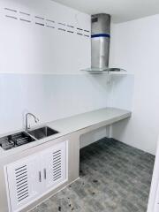 Modern white kitchen with ventilation hood, sink, and tiled floor