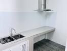 Modern white kitchen with ventilation hood, sink, and tiled floor