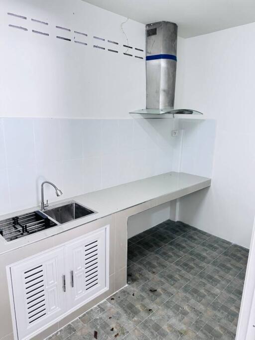 Modern white kitchen with ventilation hood, sink, and tiled floor