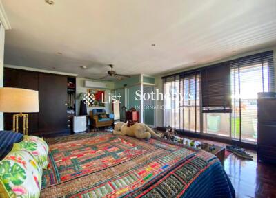 Spacious bedroom with colorful bedspread, large windows, and balcony access.