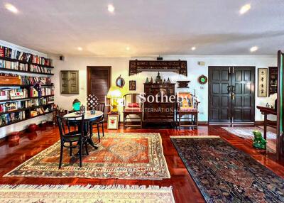 Spacious and well-decorated living room with multiple rugs, bookshelves, and seating areas