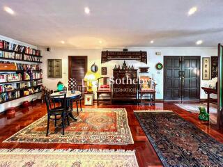 Spacious and well-decorated living room with multiple rugs, bookshelves, and seating areas