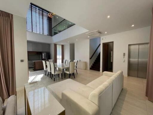 Modern living room with dining area, staircase, and elevator