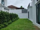 Well-maintained grassy yard between buildings with trimmed hedges