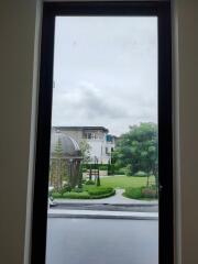 View of an outdoor garden and neighboring building from a window