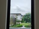 View of an outdoor garden and neighboring building from a window