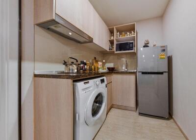 Modern kitchen with wooden cabinets, countertop appliances, and a washing machine