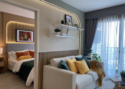 Modern living room with sofa, decorative pillows, shelves, and adjoining bedroom