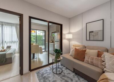 Modern living room with a sofa, side table, and view of an adjacent bedroom and dining area