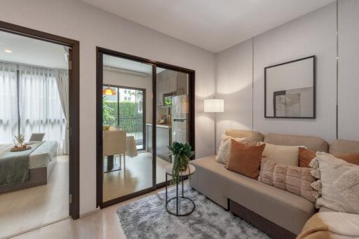 Modern living room with a sofa, side table, and view of an adjacent bedroom and dining area