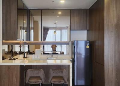 Modern kitchen with bar stools, stainless steel refrigerator, and ample storage